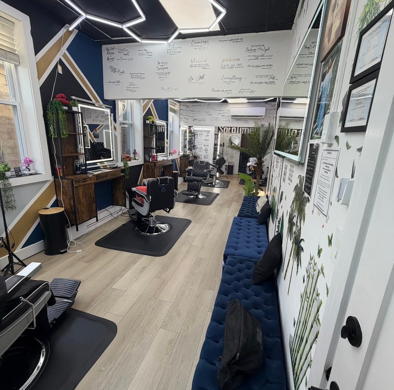 Inside Soto Time Cuts: barber chairs, a blue tufted bench, and scripture lettered across the walls